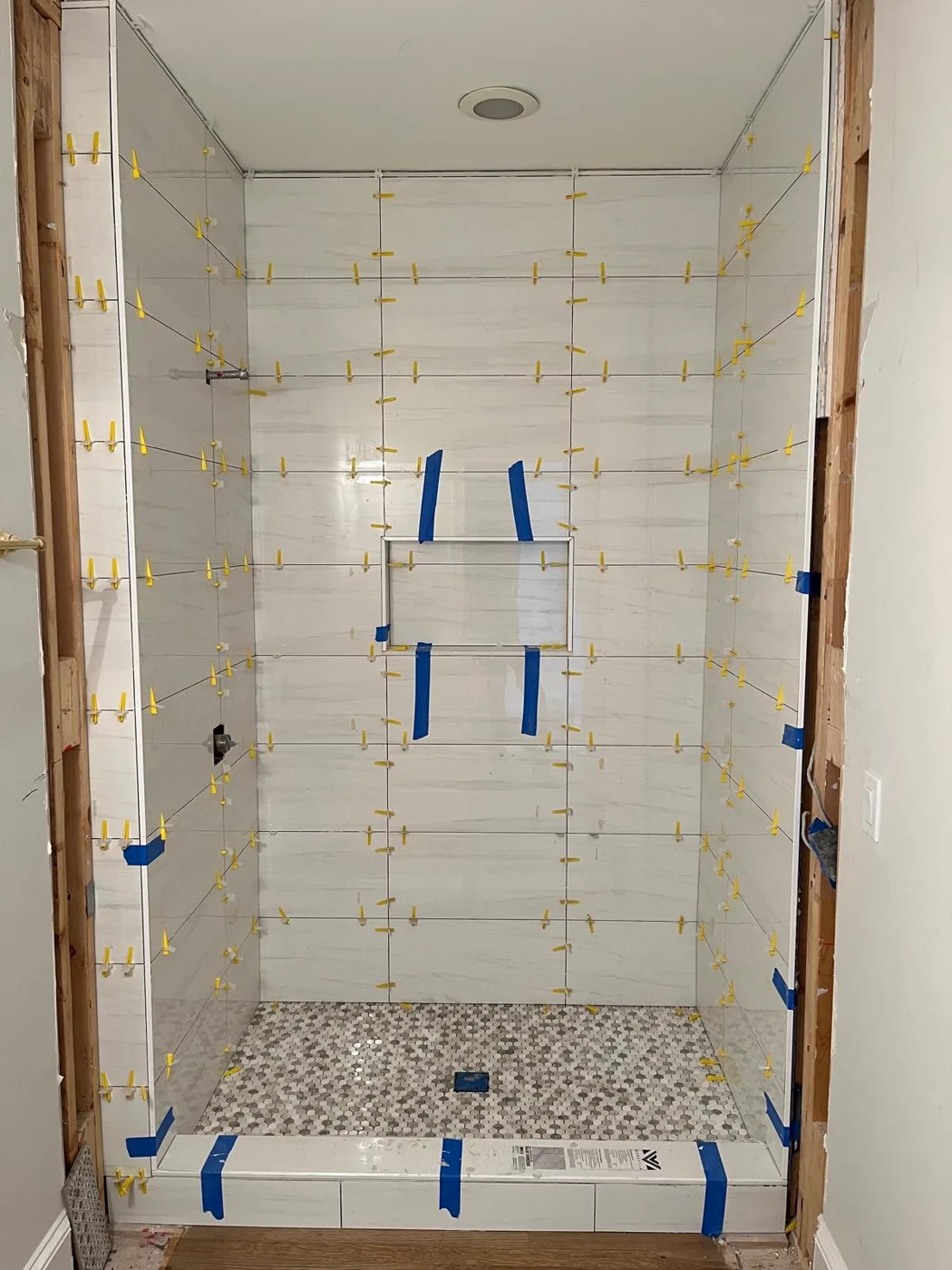 Tile setting in progress in the shower during a master bathroom remodel, spacers visible between the tiles, Metro Atlanta
