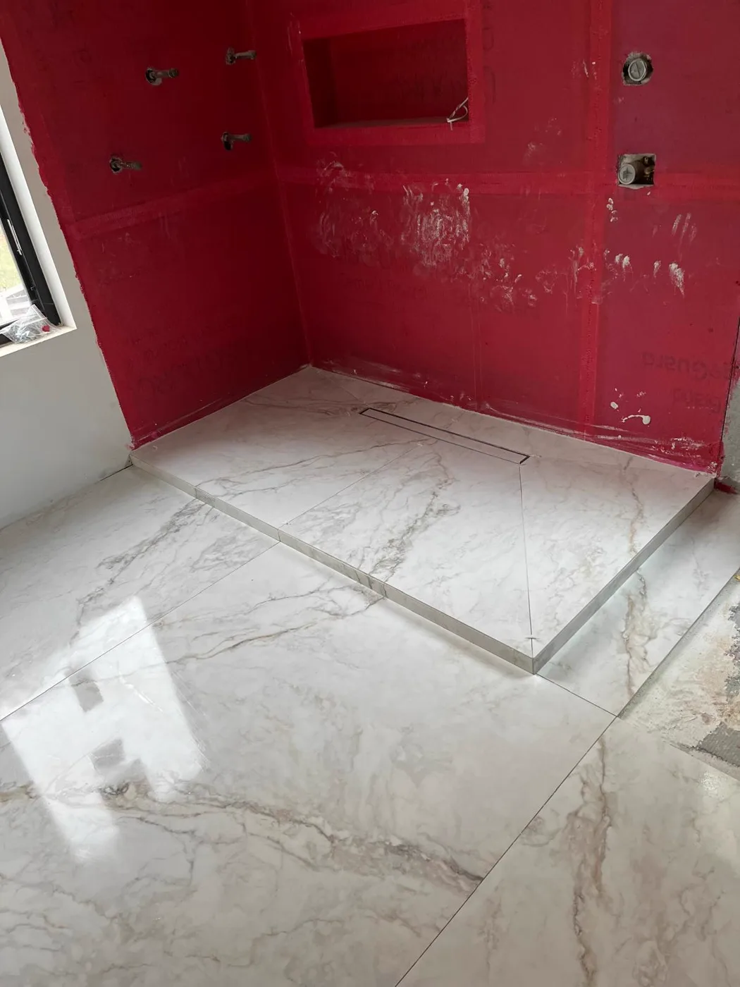 Red waterproofing membrane applied in a shower before tile, commercial venue renovation, Metro Atlanta
