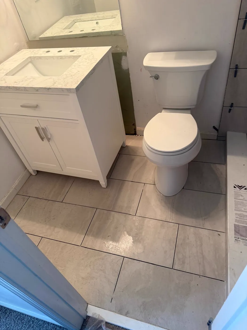 Finished bathroom with a white vanity, new toilet and large-format tile floor, Metro Atlanta