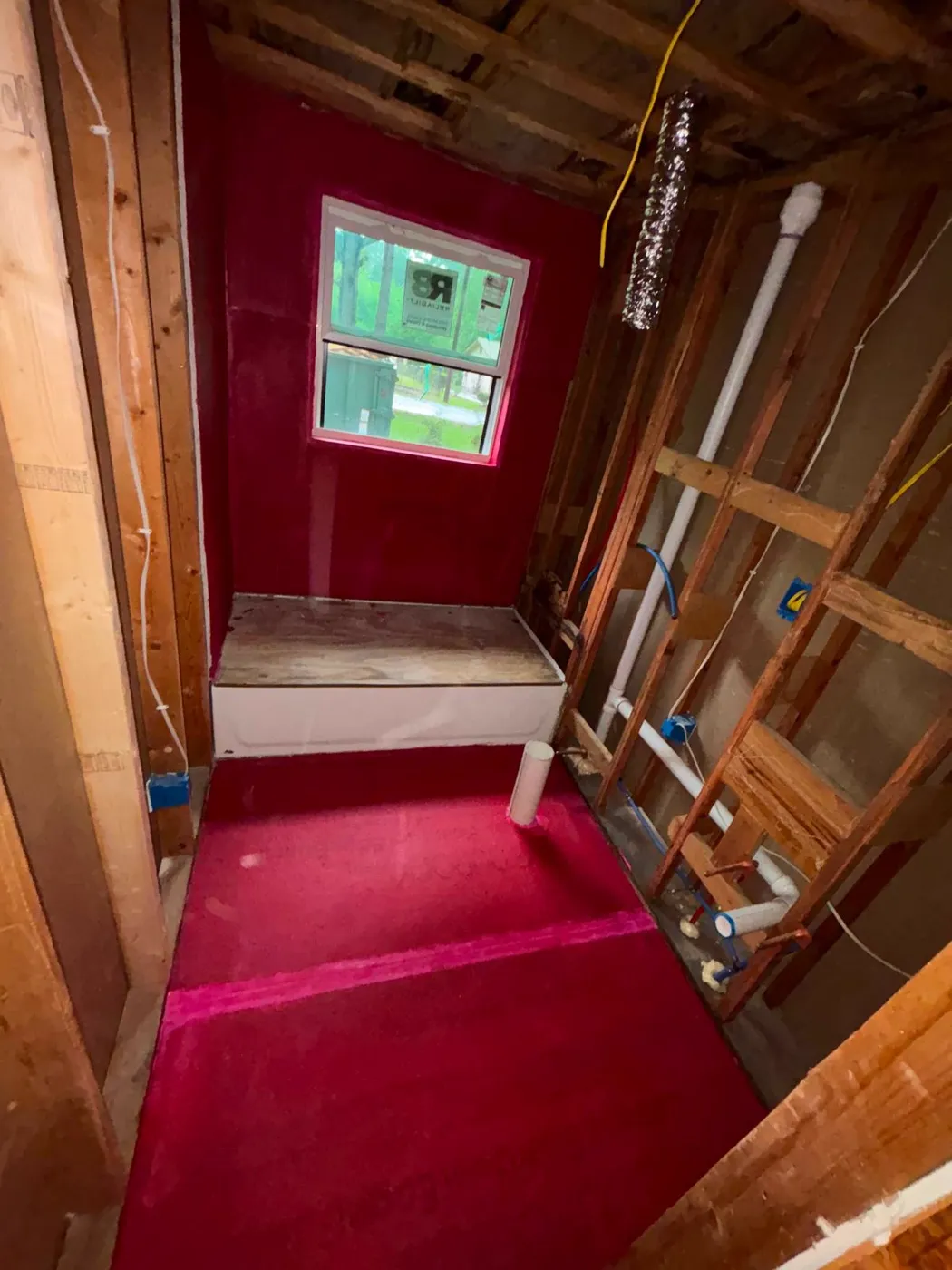 Shower area with red waterproofing membrane applied over the pan and walls before tile, Metro Atlanta
