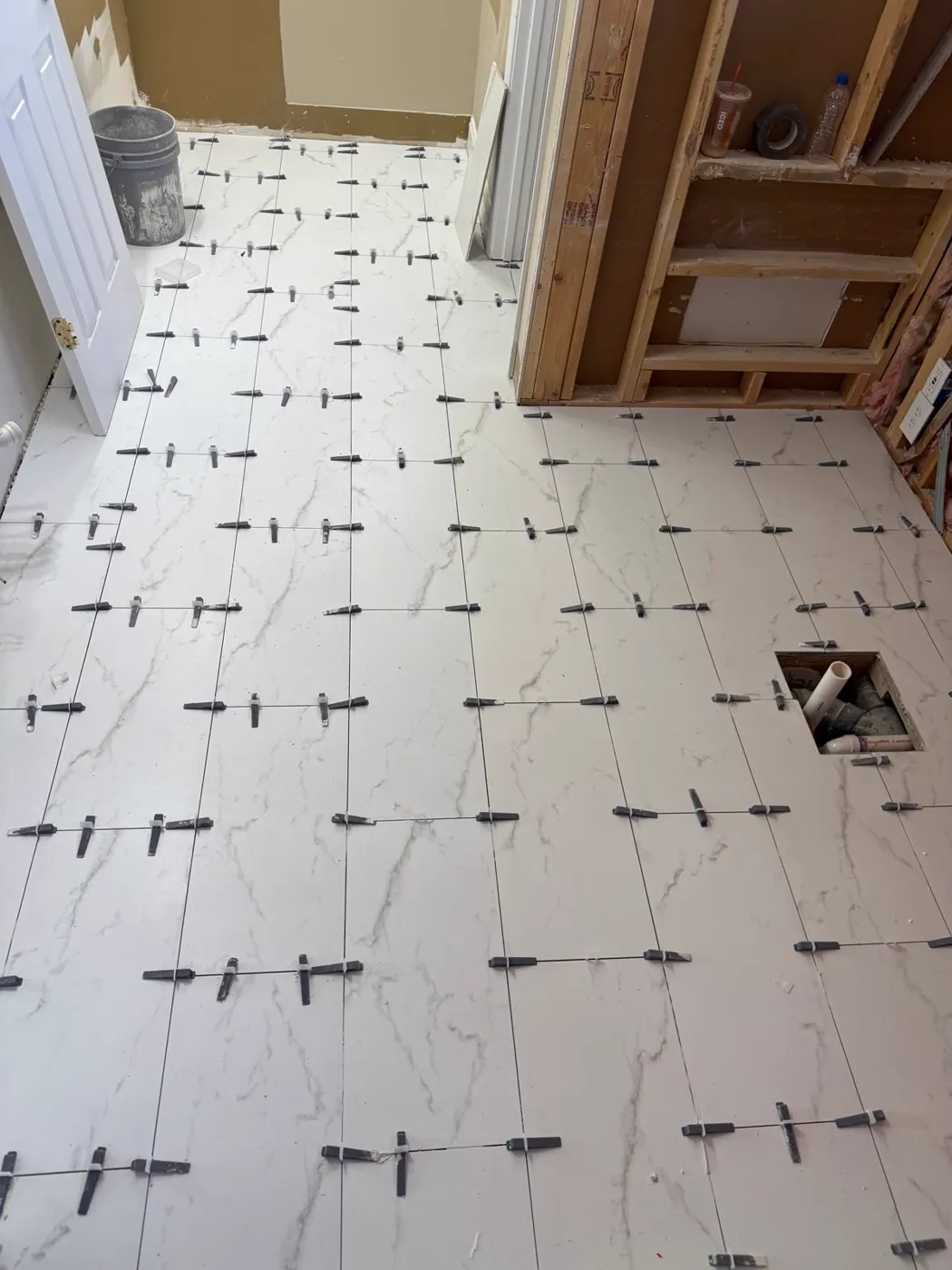 Large-format marble-look floor tile being set with levelling spacers, Metro Atlanta